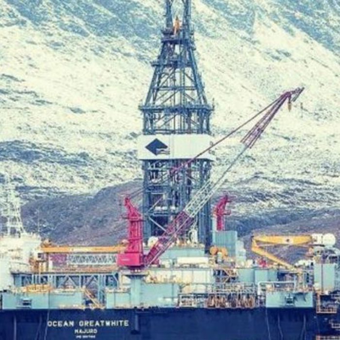 Oil rig "Ocean Greatwhite" operates against a backdrop of snow-covered mountains, featuring various equipment and structures used in offshore drilling.
