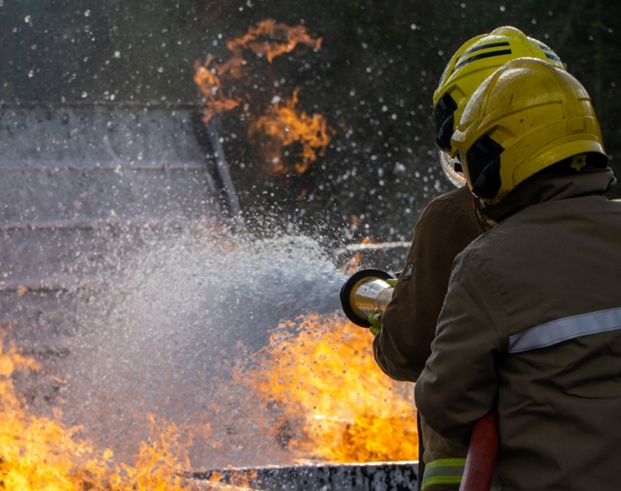 dos bomberos apagando un incendio para formación en respuesta a emergencias