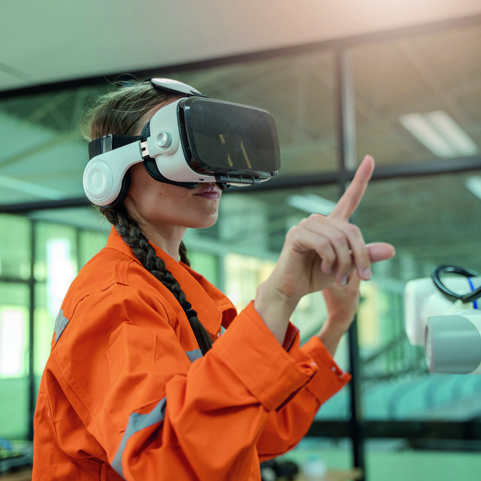 A person in an orange jacket and virtual reality headset is immersed in a digital training interface, exploring a modern, well-lit room.