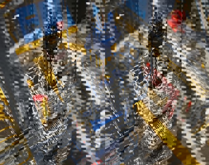 Close-up view of an offshore drilling rig showing machinery, safety barriers, and platforms with railings viewed from an elevated angle.