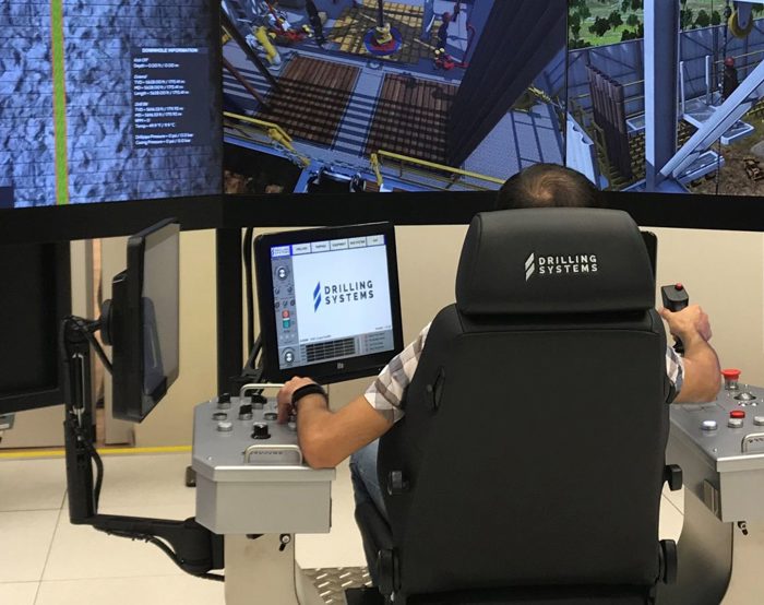 A person operates a high-tech drilling simulation system with multiple screens and control panels, likely used for training or testing purposes.