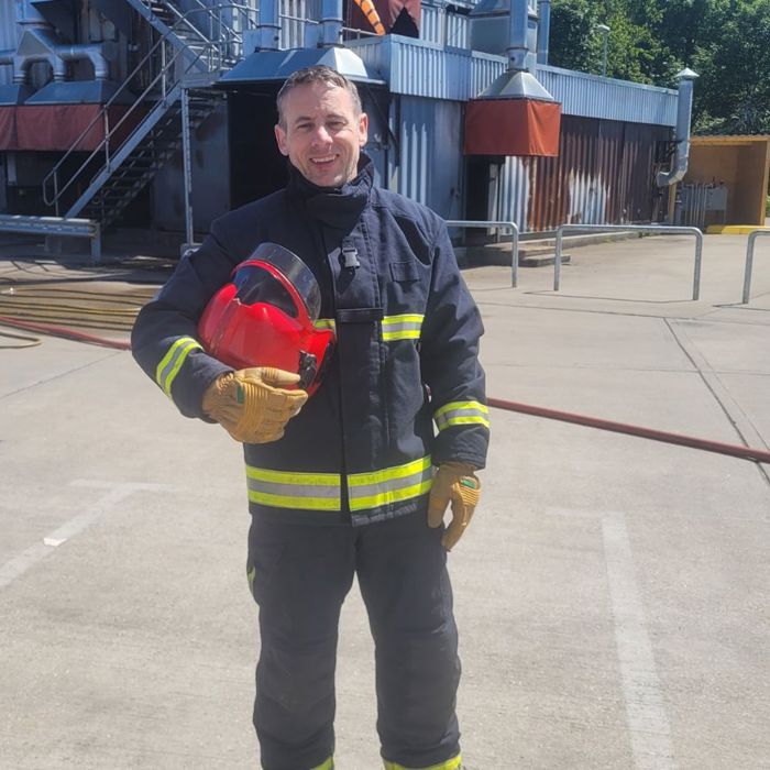 firefighter holding helmet in front of helideck fire training ground